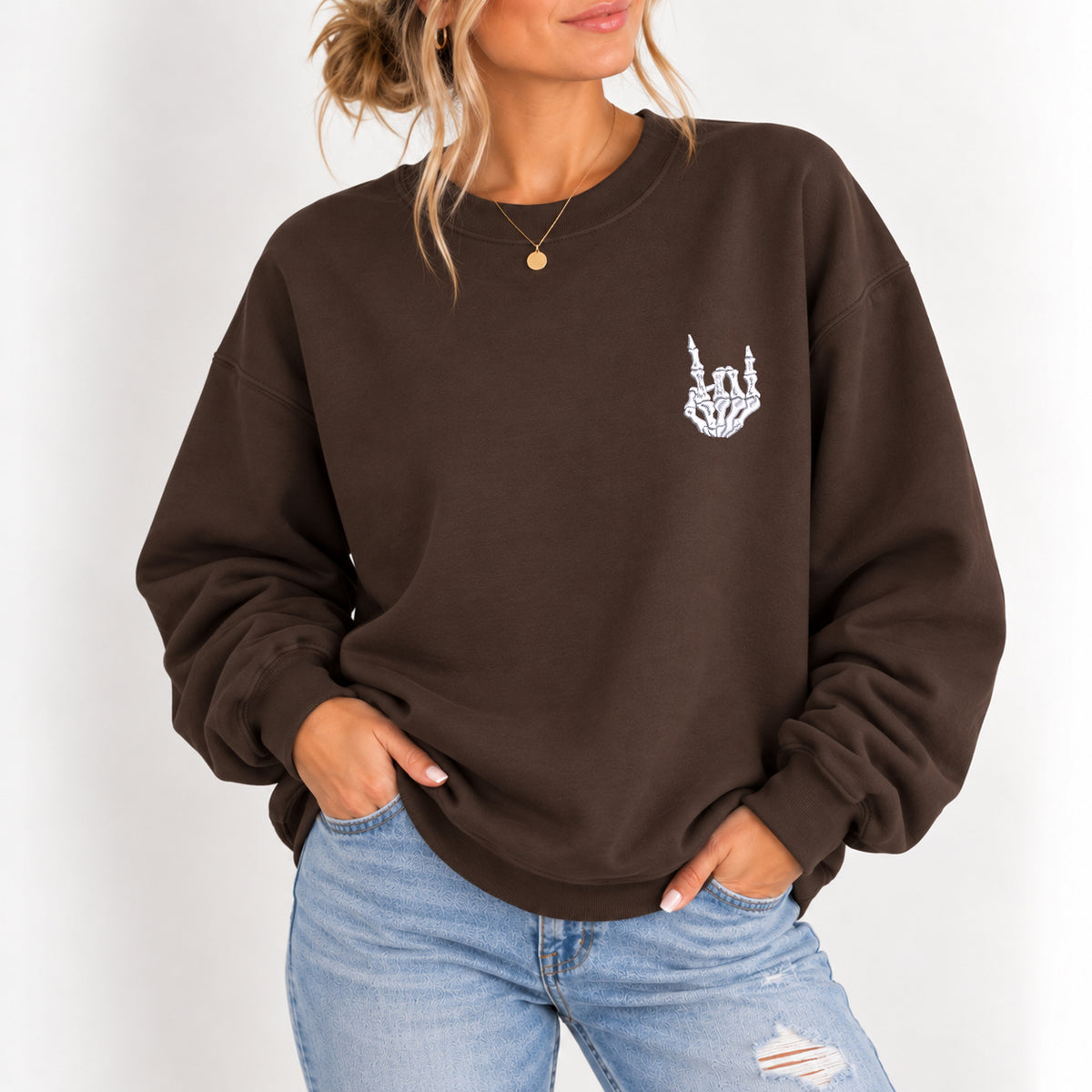 Woman wearing the Rock On Skeleton Hand embroidered crewneck sweatshirt in Dark Chocolate with jeans