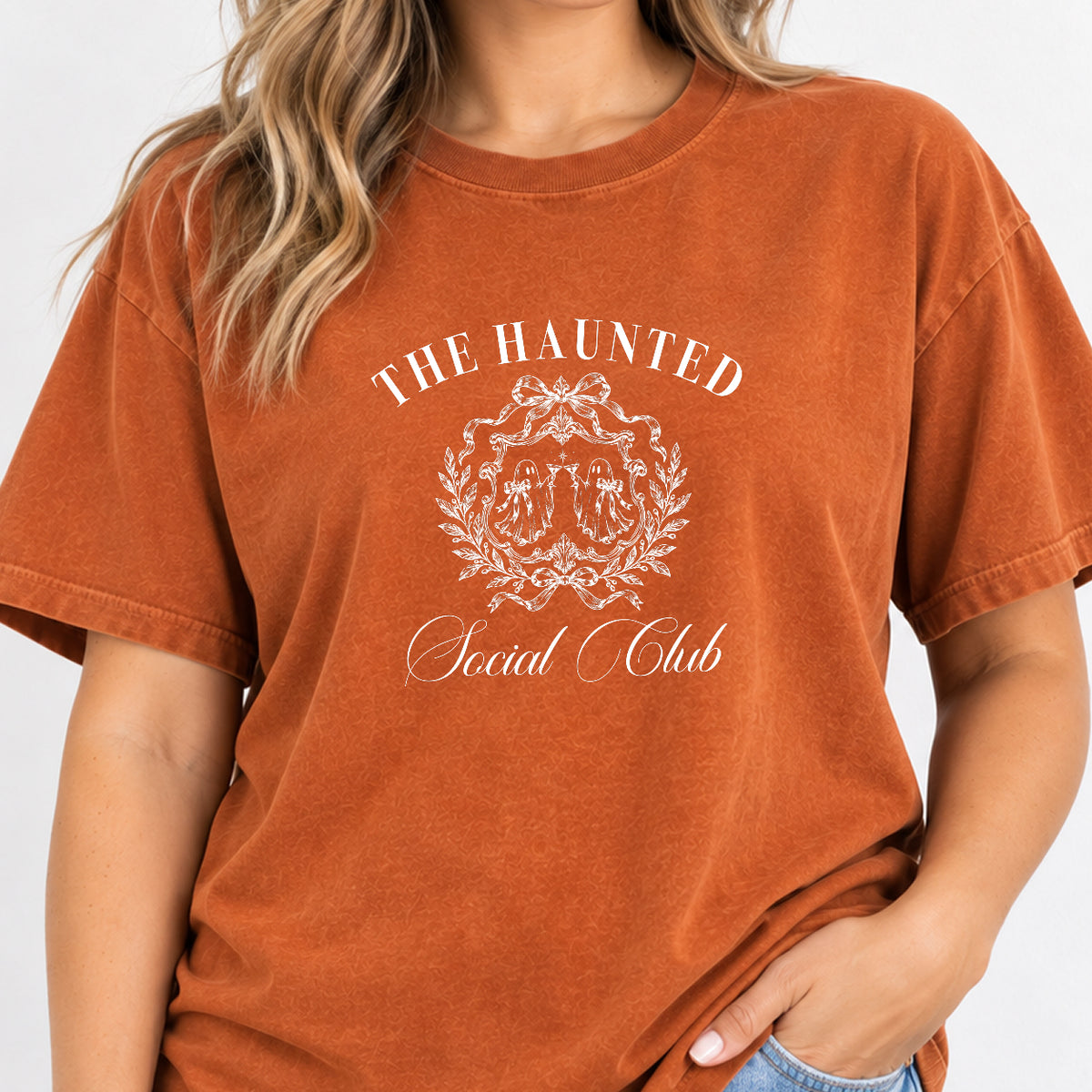 Woman wearing The Haunted Social Club crest tee in Yam (burnt orange)