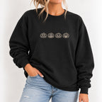Woman wearing the jack-o-lantern embroidered crewneck sweatshirt in Black with jeans