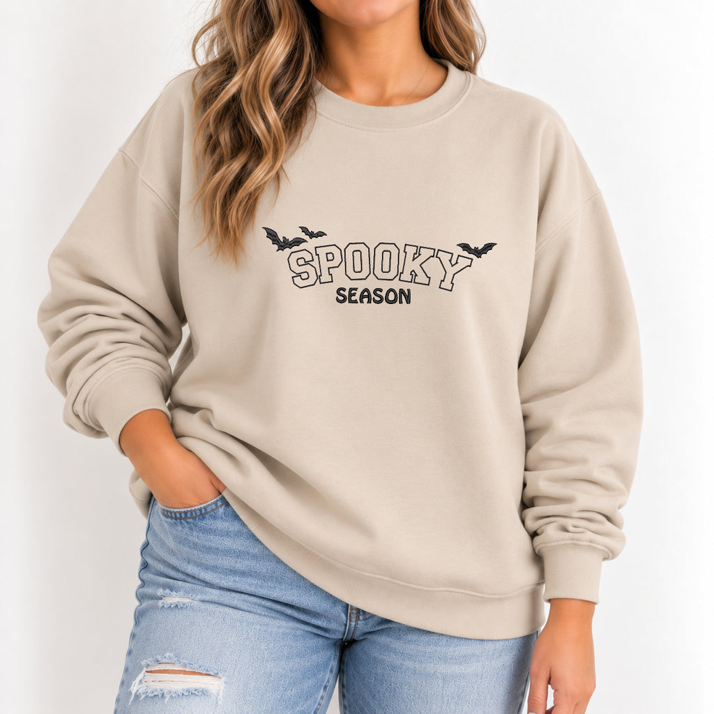 Woman wearing the Spooky Season embroidered crewneck sweatshirt in Sand with jeans, black thread