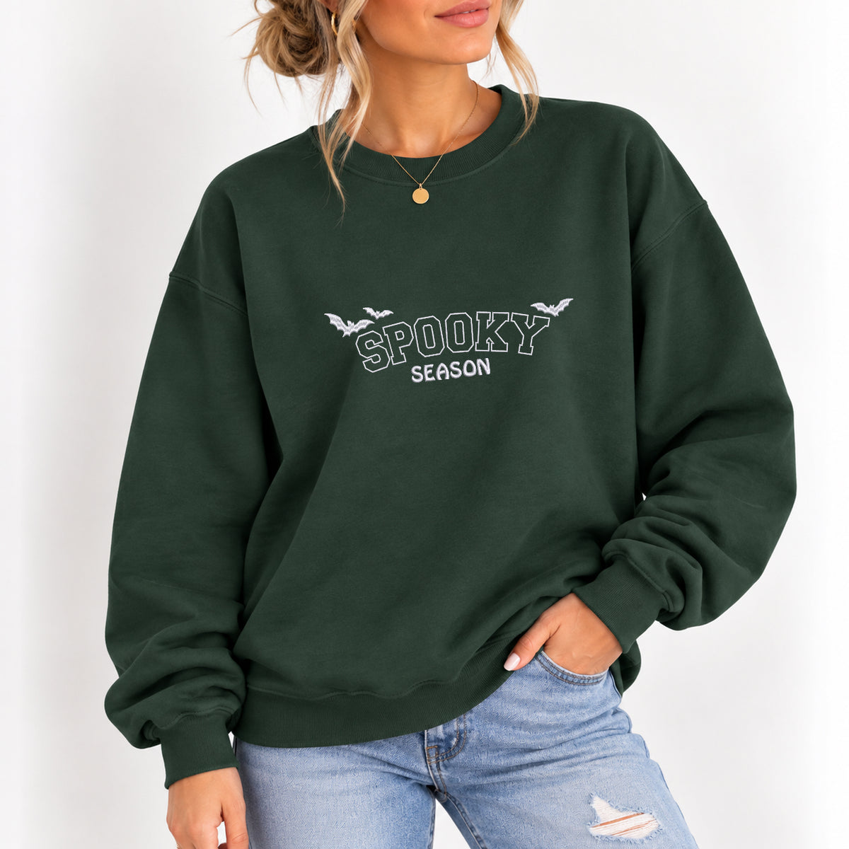 Woman wearing the Spooky Season embroidered crewneck sweatshirt in Forest Green with jeans