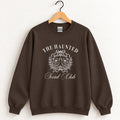 The Haunted Social Club crewneck sweatshirt in Dark Chocolate on a wooden hanger
