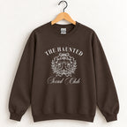 The Haunted Social Club crewneck sweatshirt in Dark Chocolate on a wooden hanger
