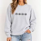 Woman wearing the jack-o-lantern embroidered crewneck sweatshirt in Ash with jeans, black thread pumpkins