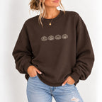 Woman wearing the jack-o-lantern embroidered crewneck sweatshirt in Dark Chocolate with jeans