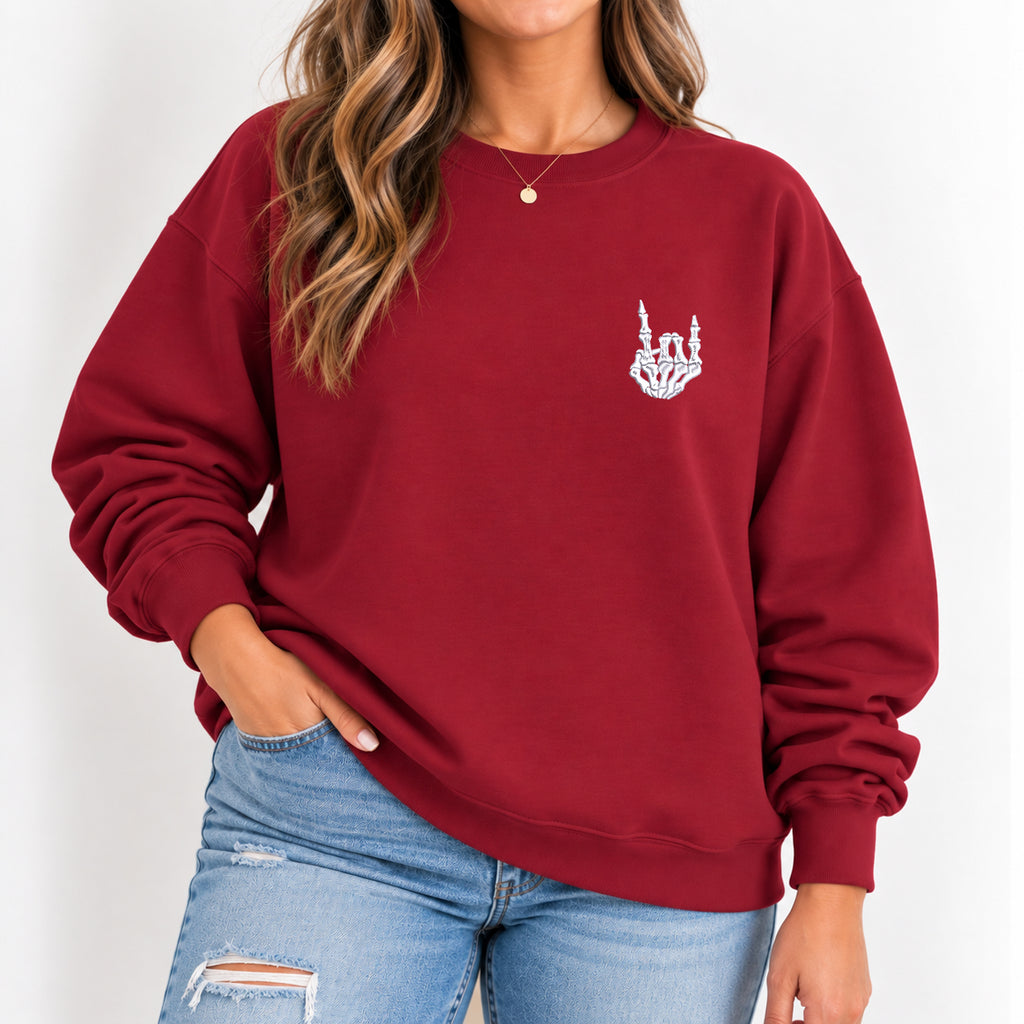 Woman wearing the Rock On Skeleton Hand embroidered crewneck sweatshirt in Cardinal Red with jeans