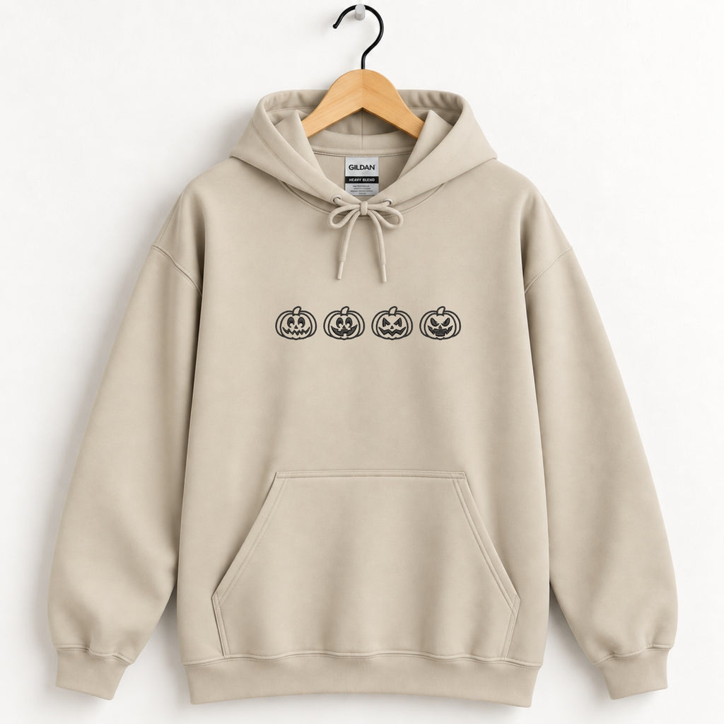 Jack-o-lantern embroidered hoodie in Sand on a wooden hanger, black thread pumpkins