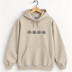 Jack-o-lantern embroidered hoodie in Sand on a wooden hanger, black thread pumpkins