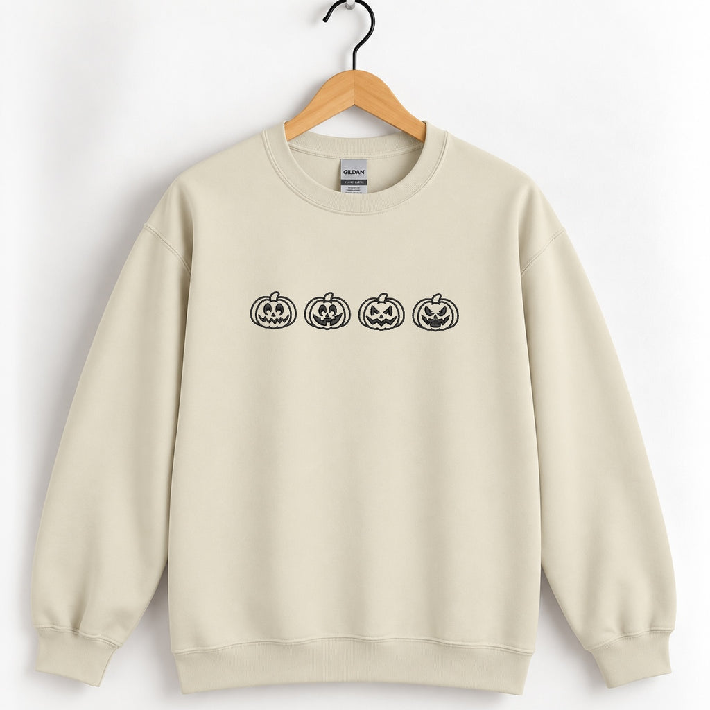 Jack-o-lantern embroidered crewneck sweatshirt in Sand on a wooden hanger, black thread pumpkins