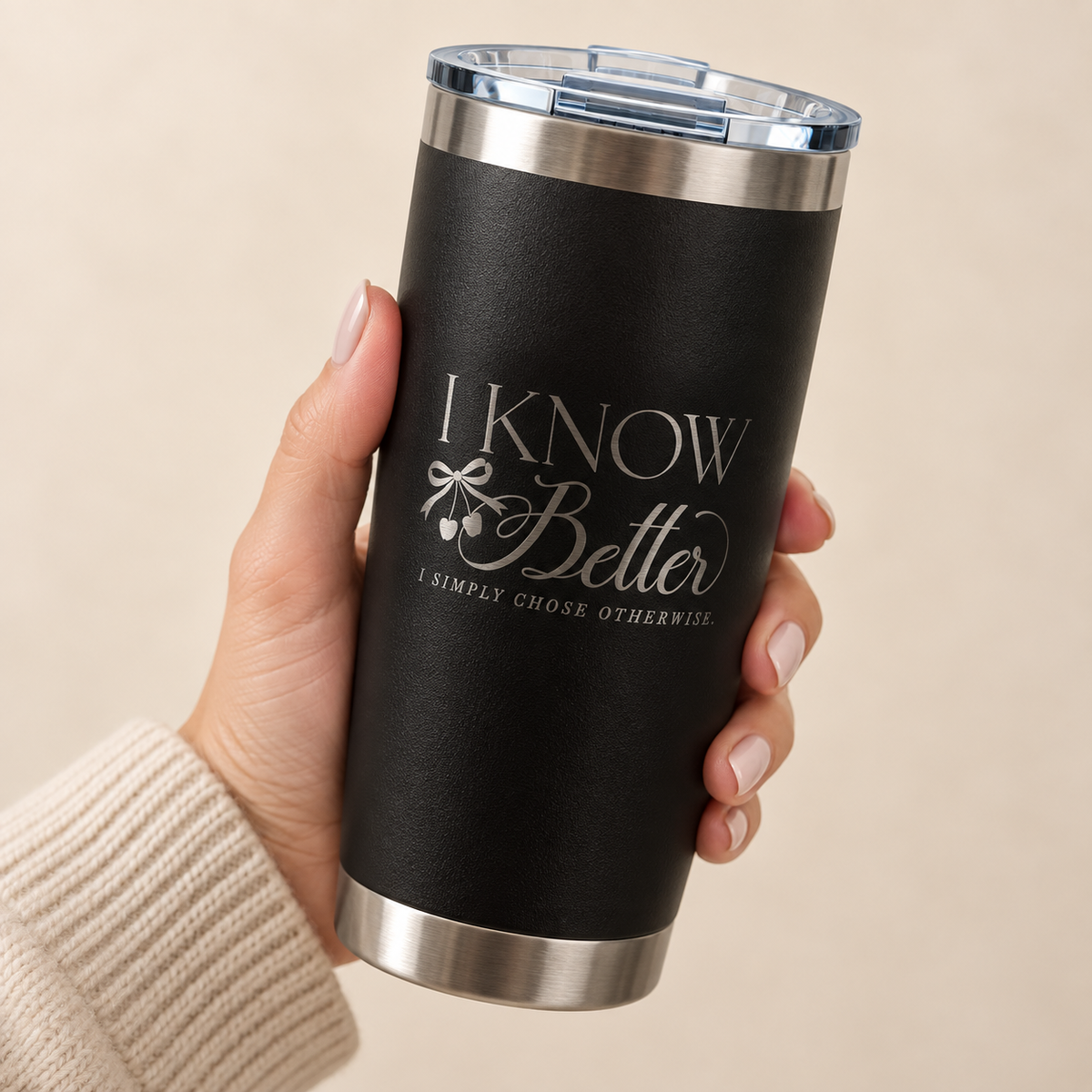 Hand holding the I Know Better, I Simply Chose Otherwise engraved 20 oz tumbler in Black, silver engraving and cherry bow