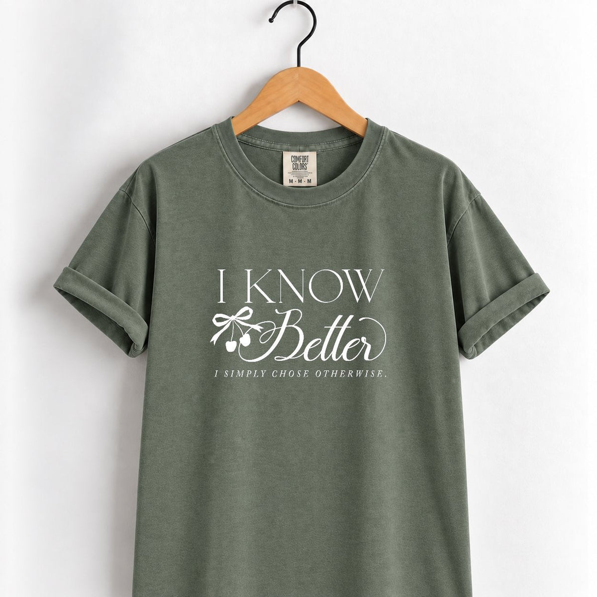 I Know Better, I Simply Chose Otherwise Comfort Colors tee in Moss on a wooden hanger, front view