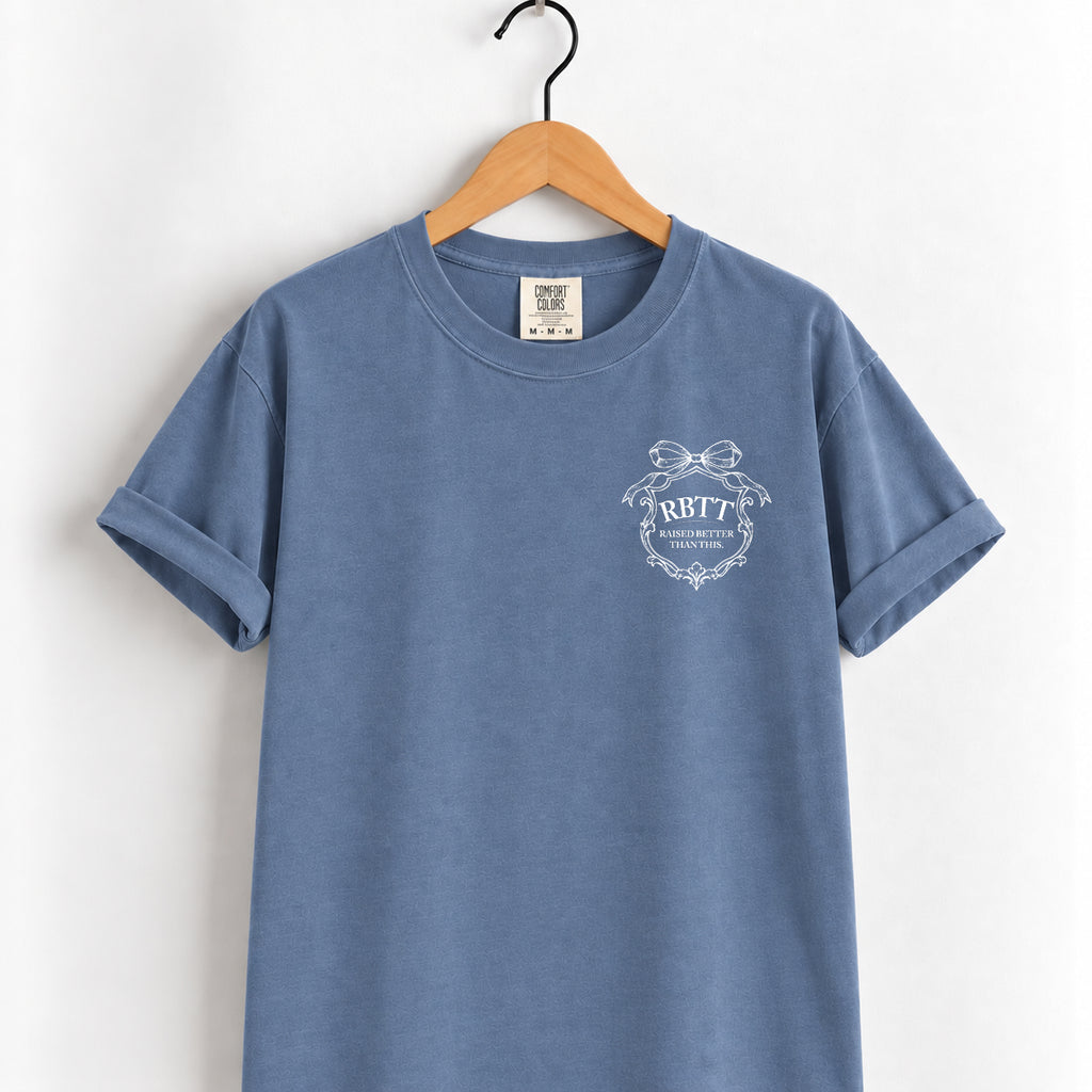 Raised Better Than This crest tee in Blue Jean on a wooden hanger, left-chest RBTT logo with bow