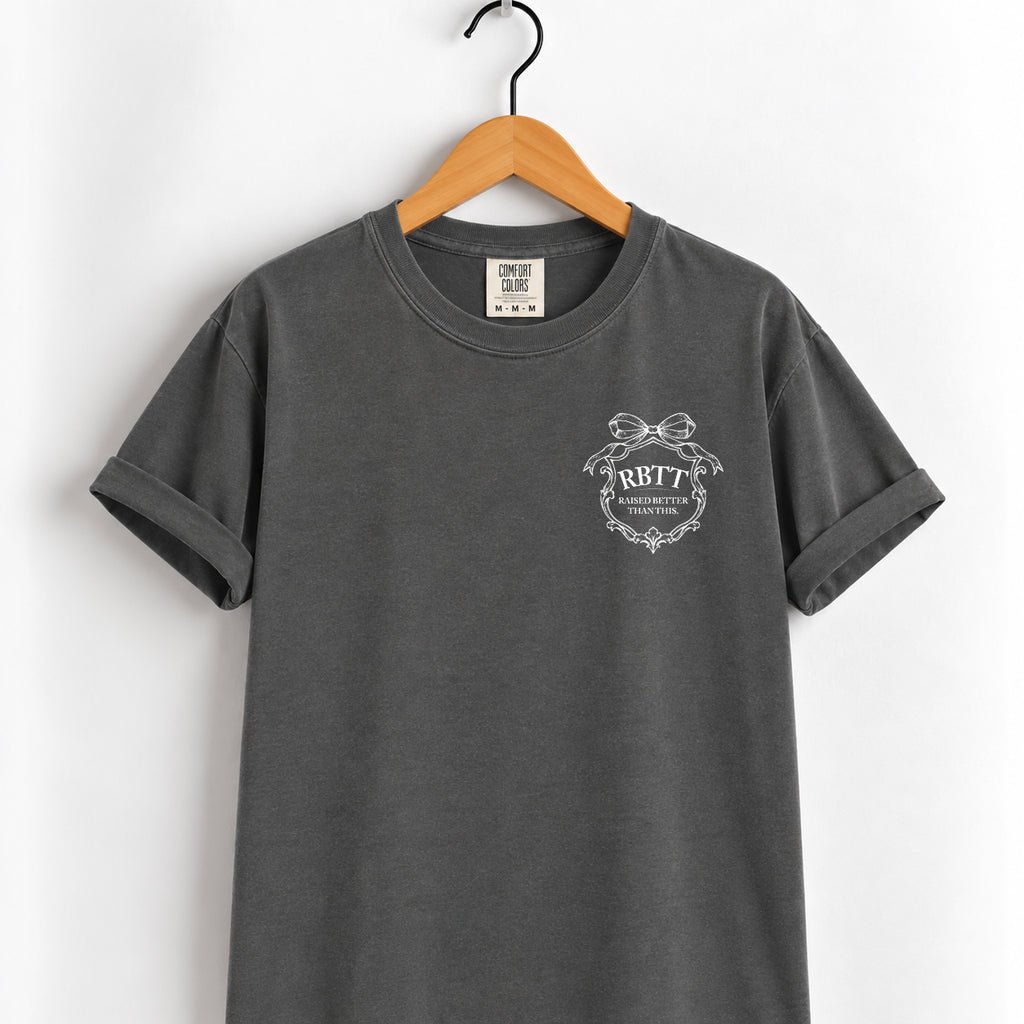 Raised Better Than This crest tee in Pepper on a wooden hanger, left-chest RBTT logo with bow
