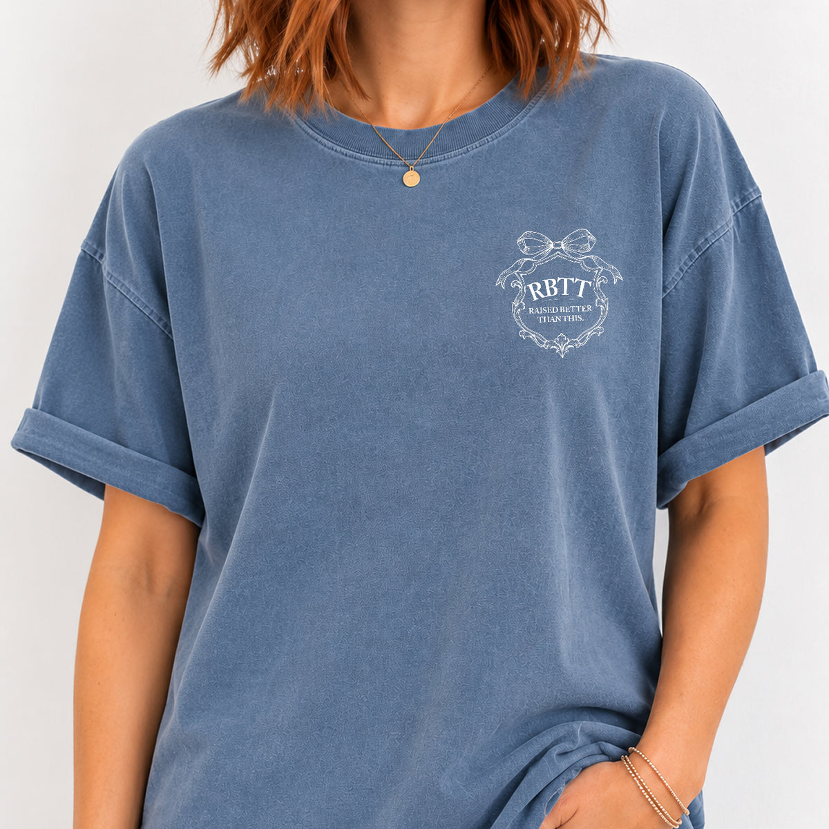 Woman wearing the Raised Better Than This crest tee in Blue Jean, relaxed fit with cuffed sleeves