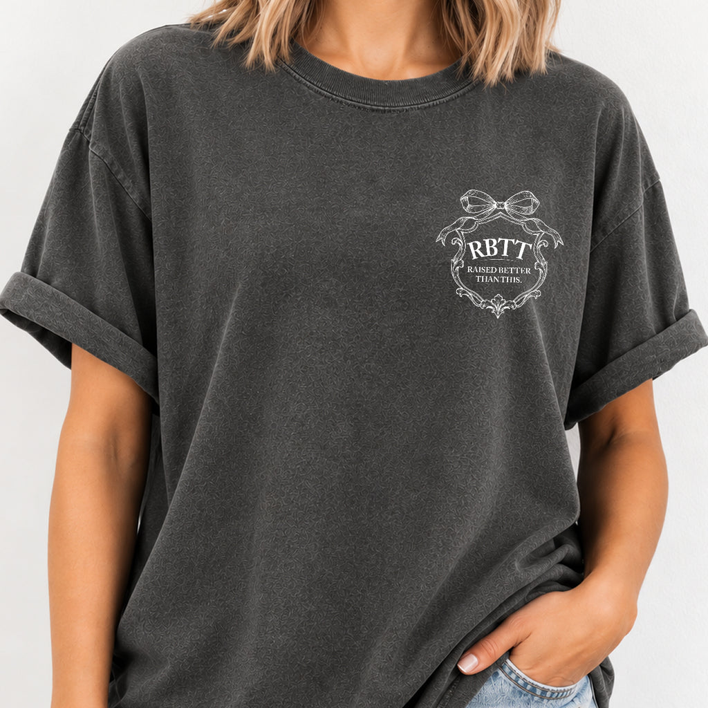 Woman wearing the Raised Better Than This crest tee in Pepper, relaxed fit with cuffed sleeves