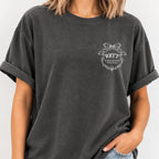 Woman wearing the Raised Better Than This crest tee in Pepper, relaxed fit with cuffed sleeves