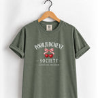 Poor Judgment Society Lifetime Member tee in Moss on a wooden hanger, cherry bow crest