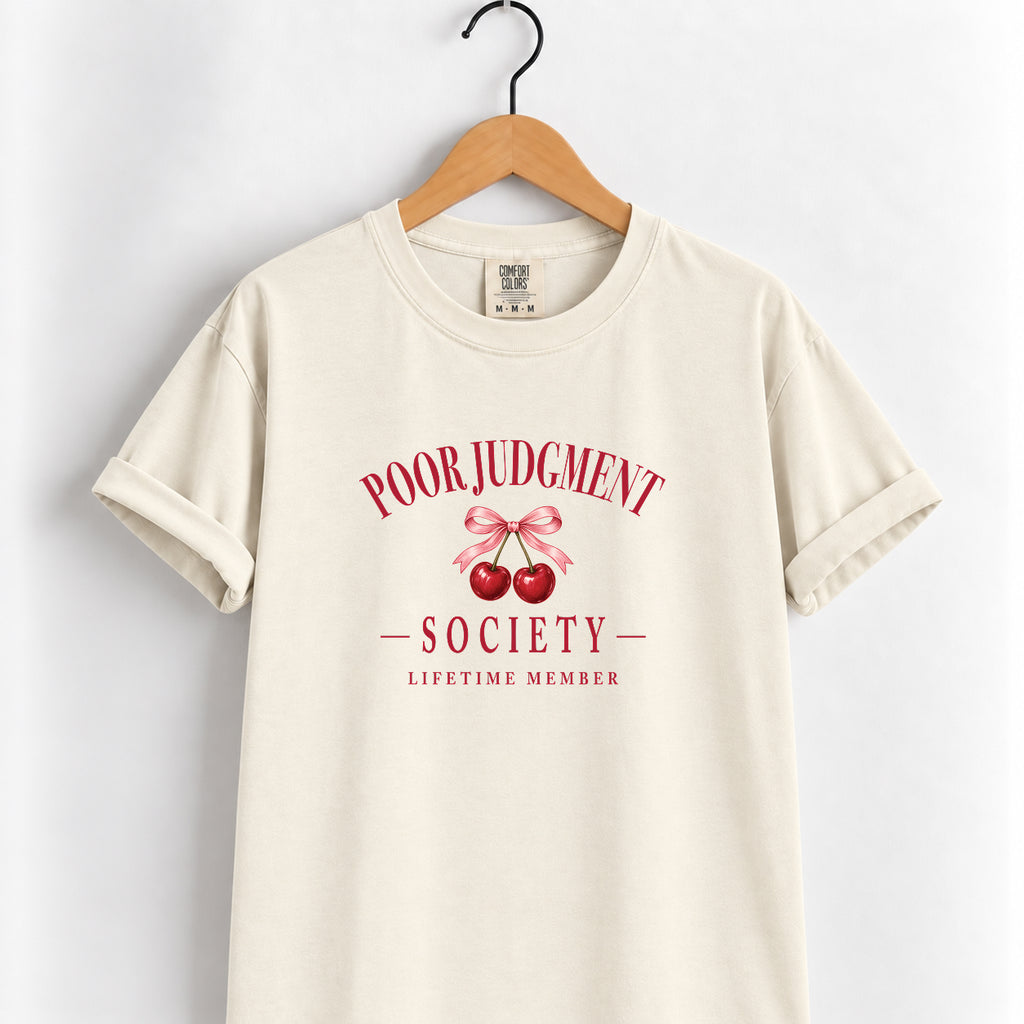 Poor Judgment Society Lifetime Member tee in Ivory on a wooden hanger, deep red lettering