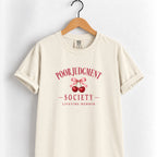 Poor Judgment Society Lifetime Member tee in Ivory on a wooden hanger, deep red lettering