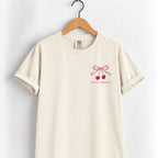 Mostly Together cherry bow tee in Ivory on a wooden hanger, left-chest print in deep red
