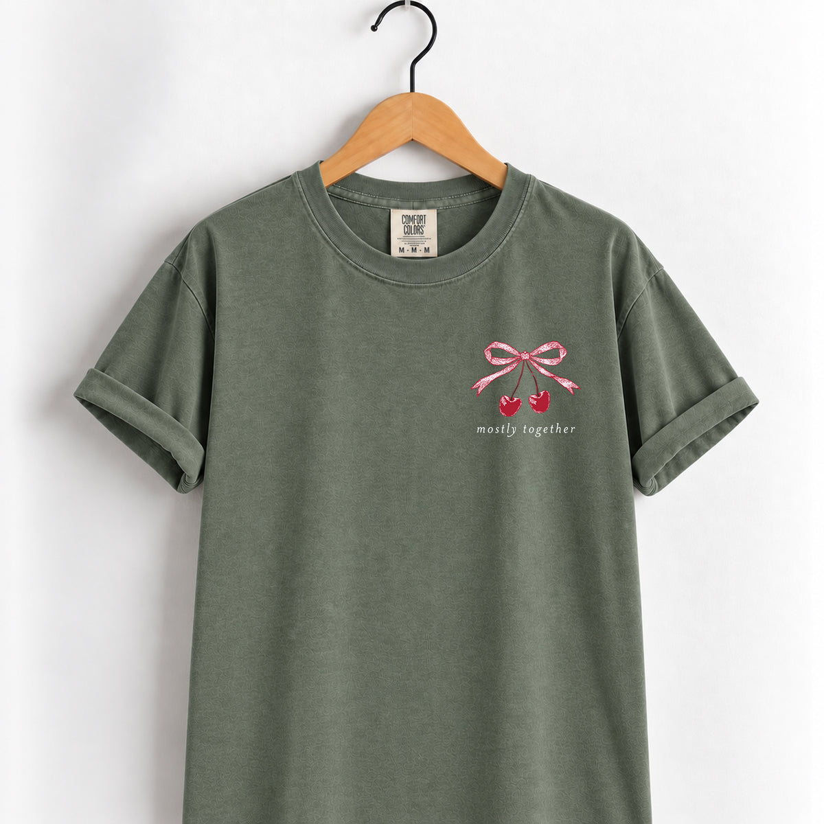 Mostly Together cherry bow tee in Moss on a wooden hanger