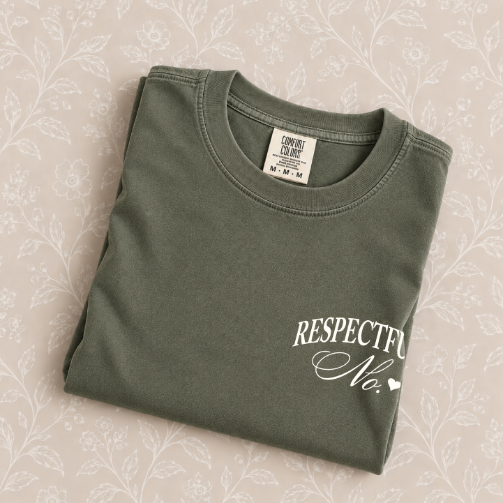 Respectfully, No tee in Moss folded on a cream floral surface, left-chest print close up