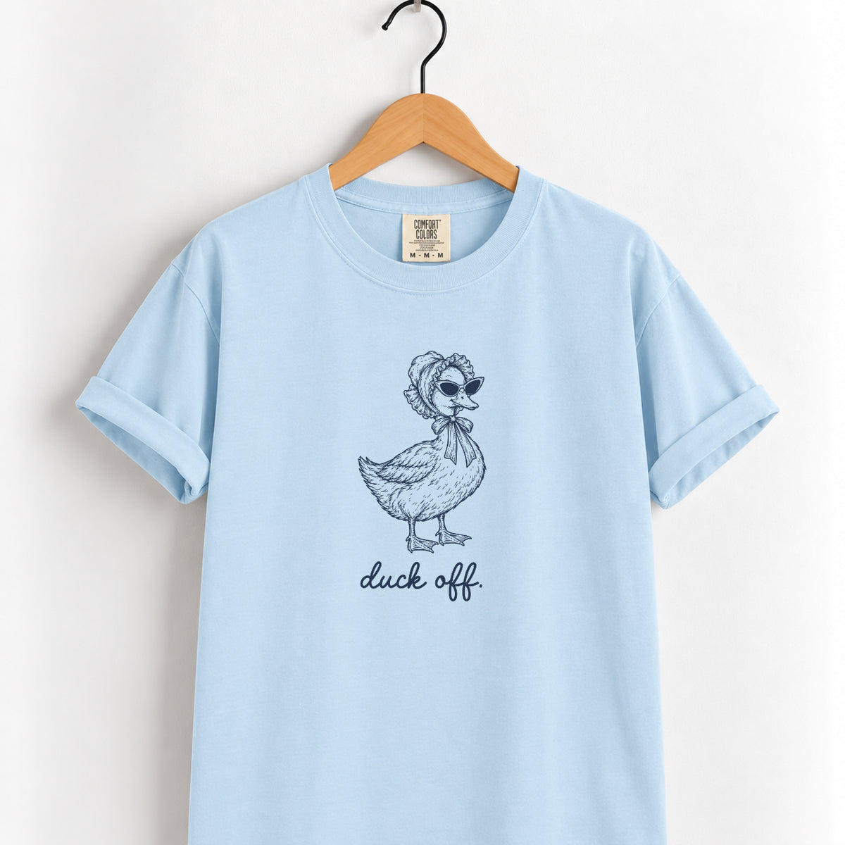 Duck Off tee in Chambray on a wooden hanger, navy duck in a bonnet and sunglasses printed center chest